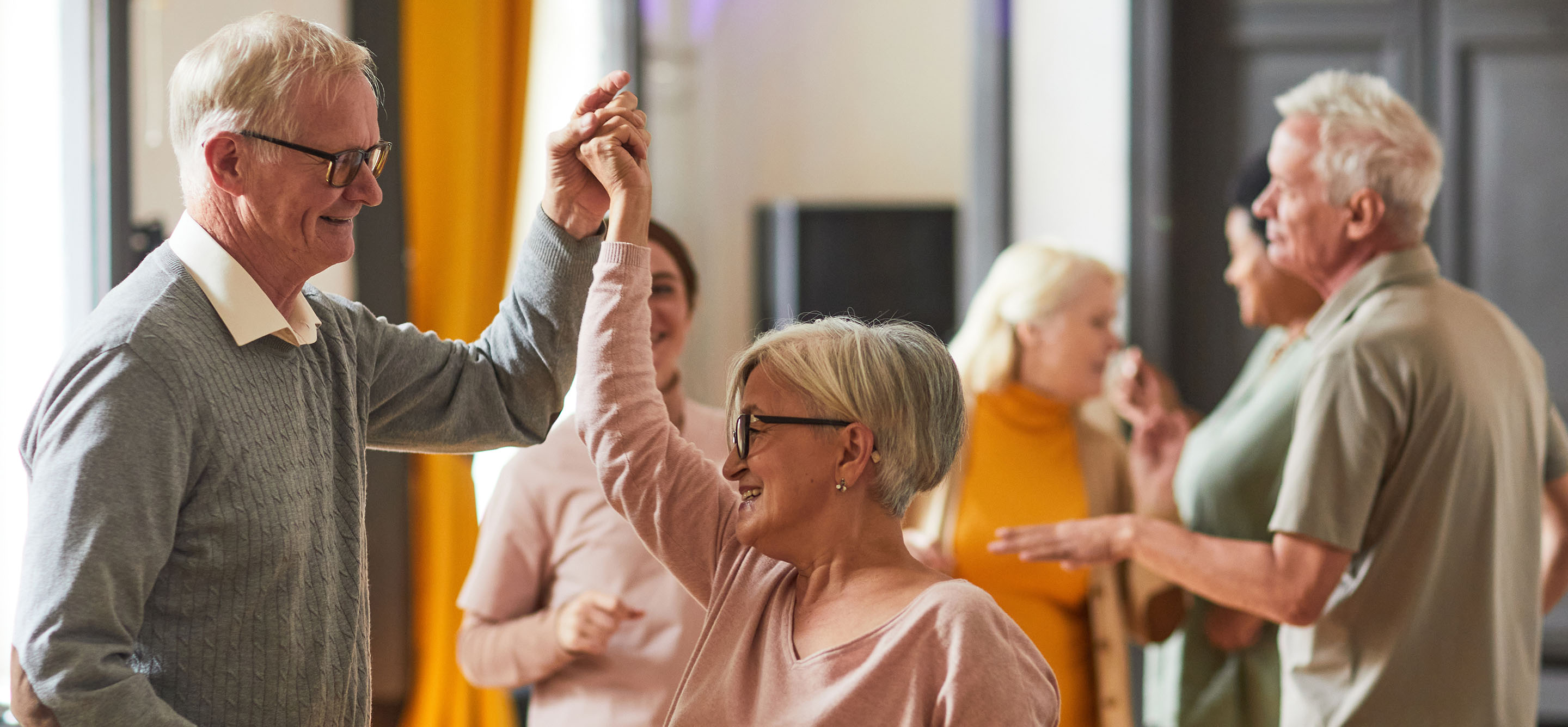 Group of smiling senior people dancing while enjoying activities in retirement home