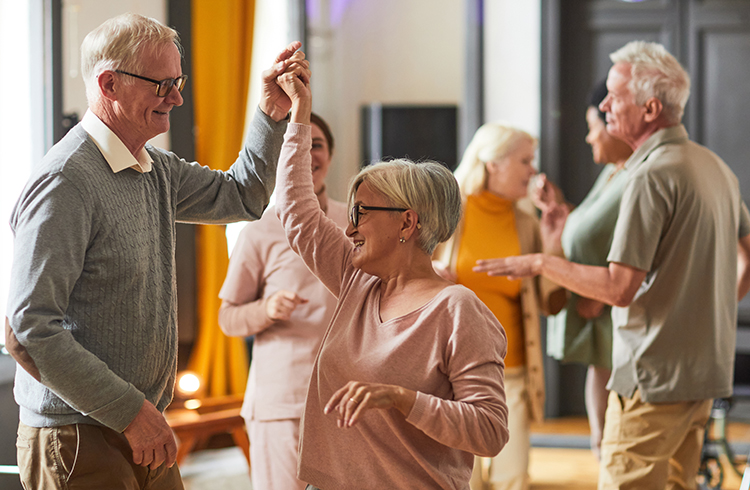 Group of smiling senior people dancing while enjoying activities in retirement home