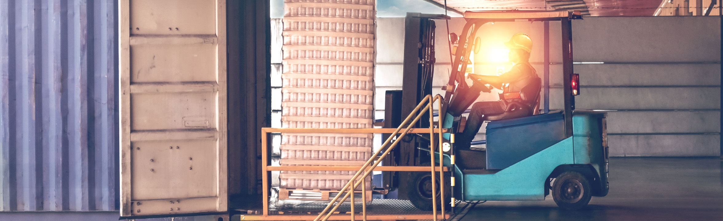 Man operating forklift in warehouse low sun shining