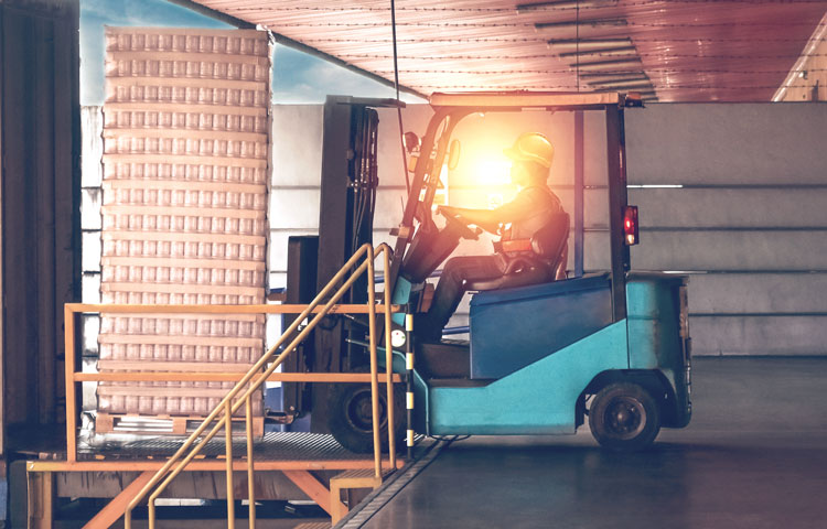 Man operating forklift in warehouse low sun shining